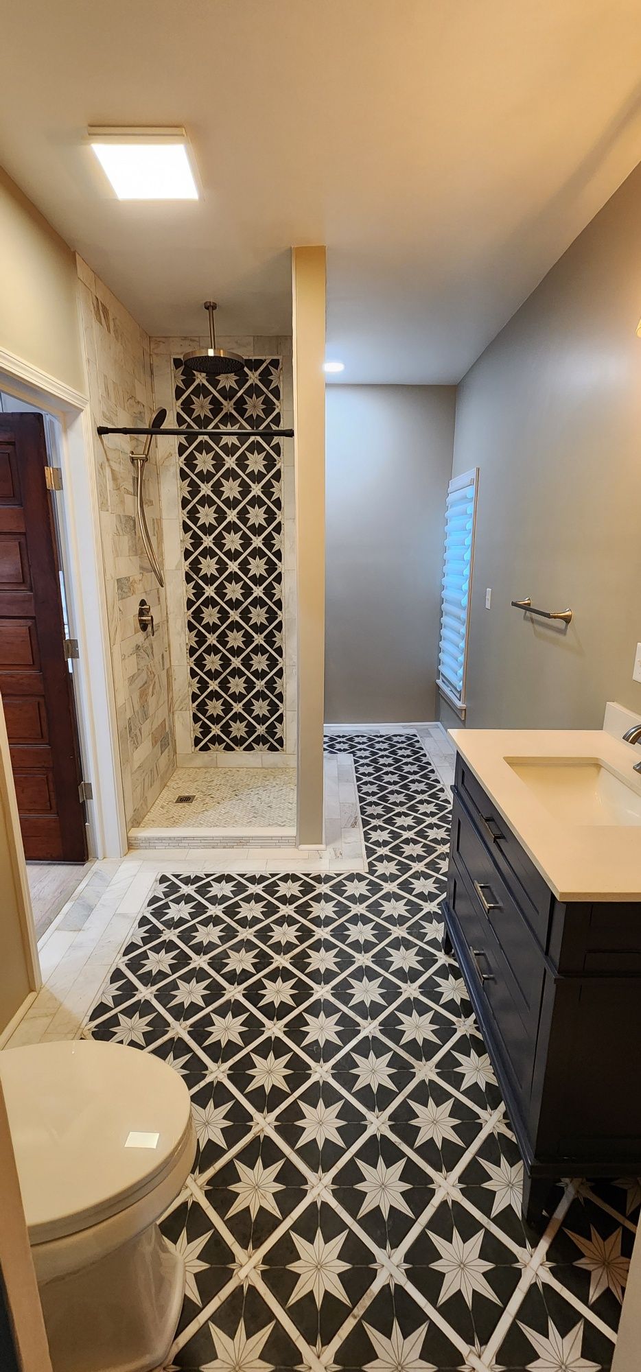 Bathroom with patterned tile floor, shower, vanity, and toilet.