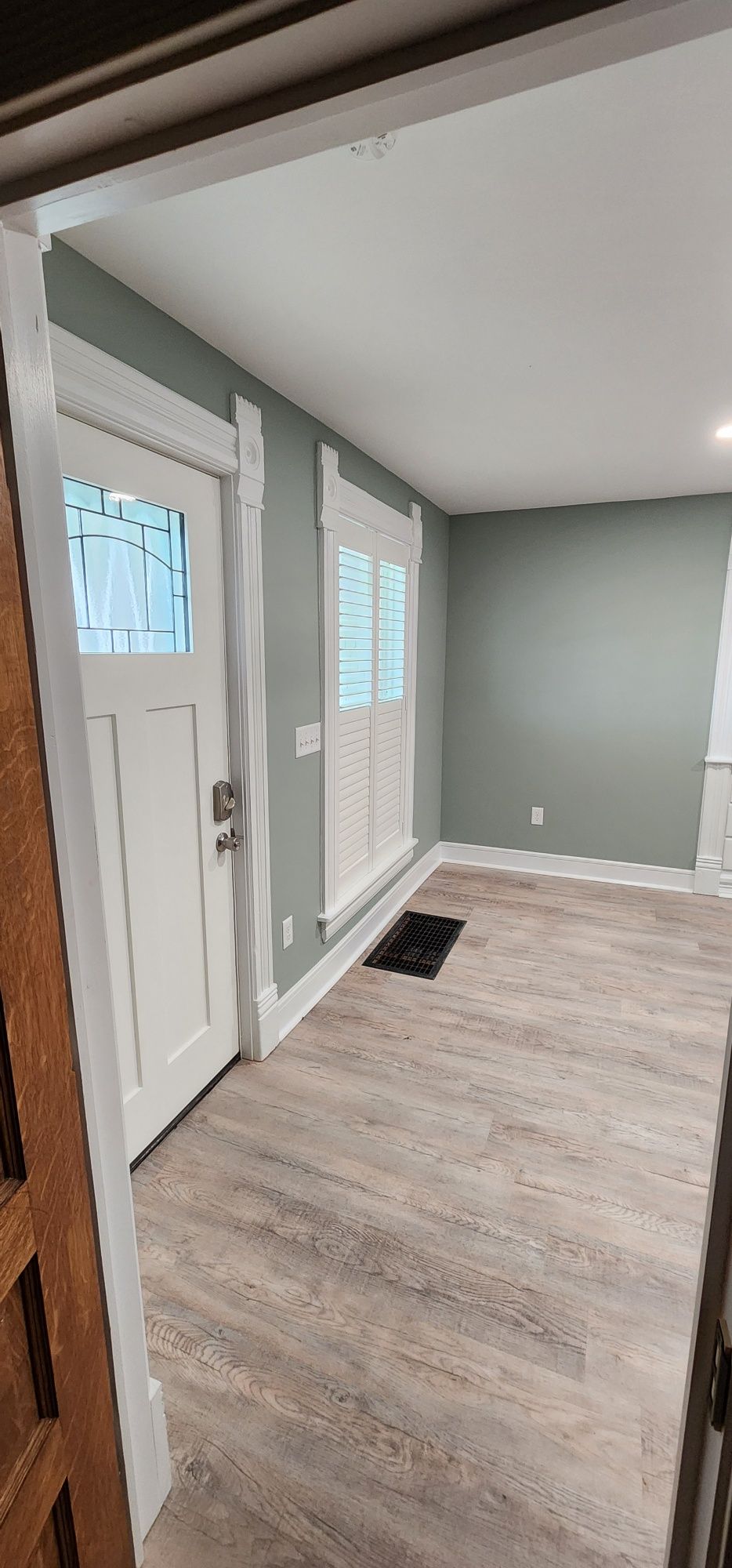 Interior view with a white door, windows, gray walls and light wood-look flooring.