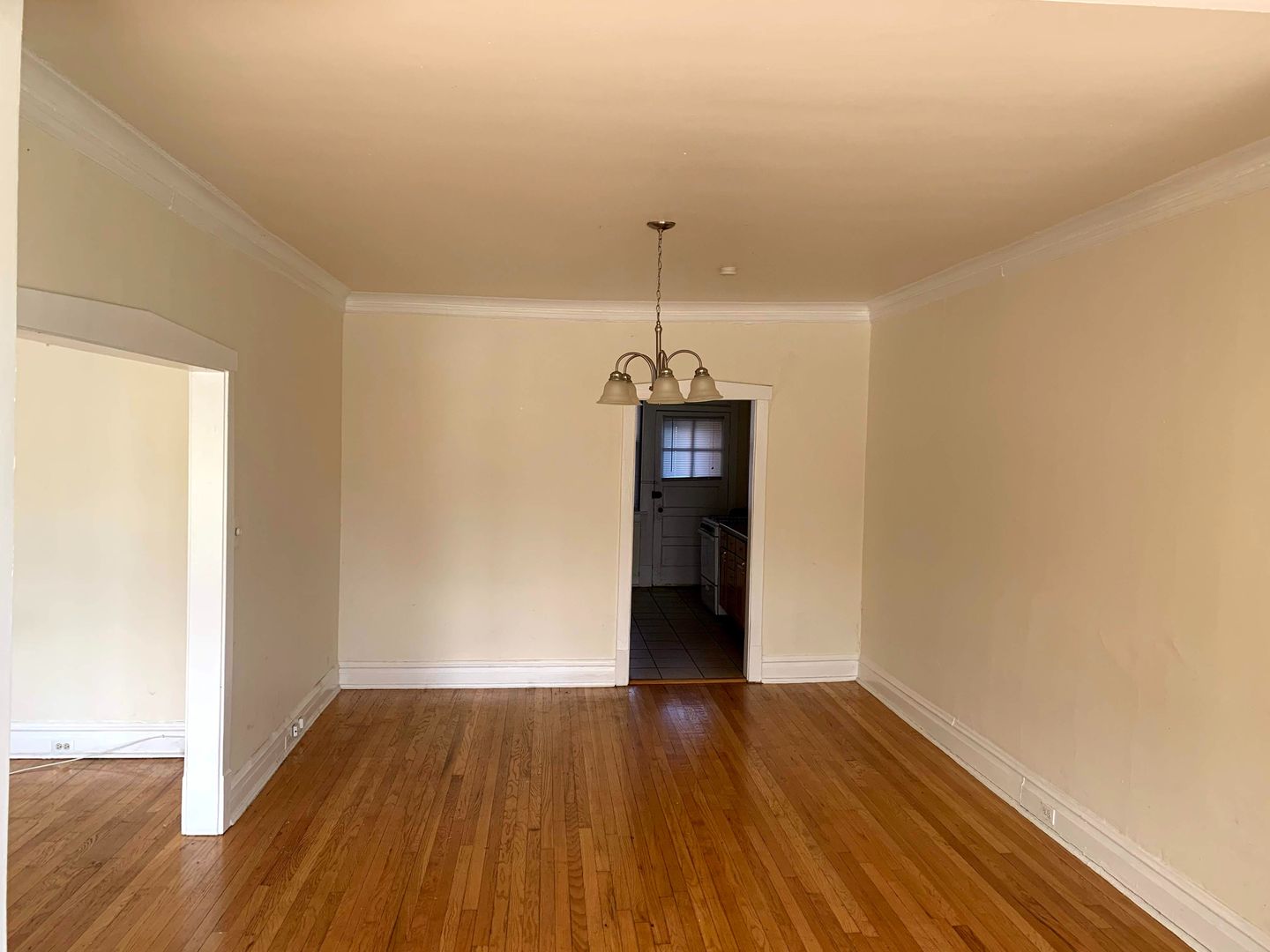 Dining room with chandelier overhead and entryway to kitchen