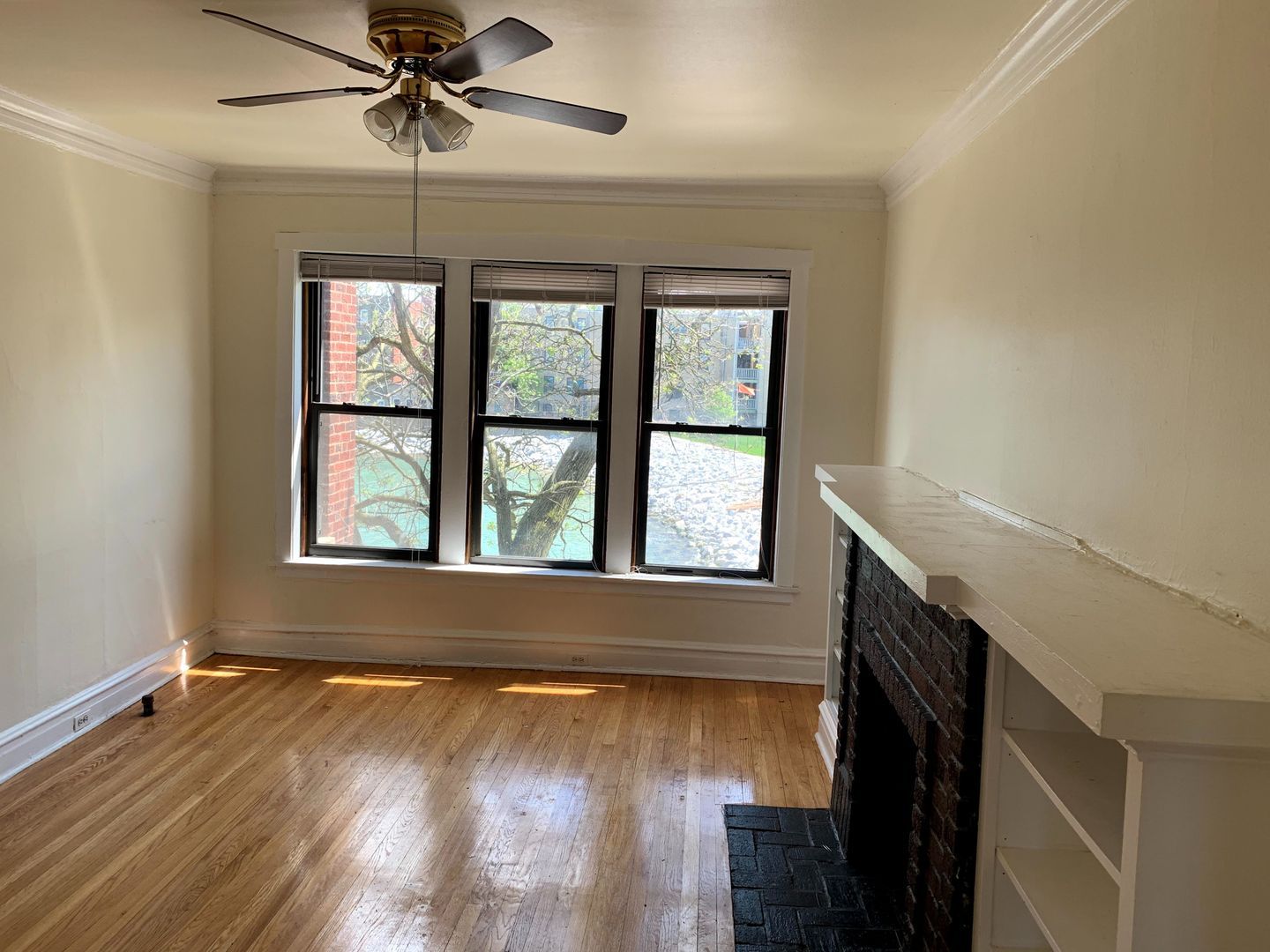 Hardwood floor living room with tall windows and brick fireplace