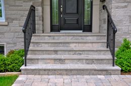 The front steps of a house with a black door