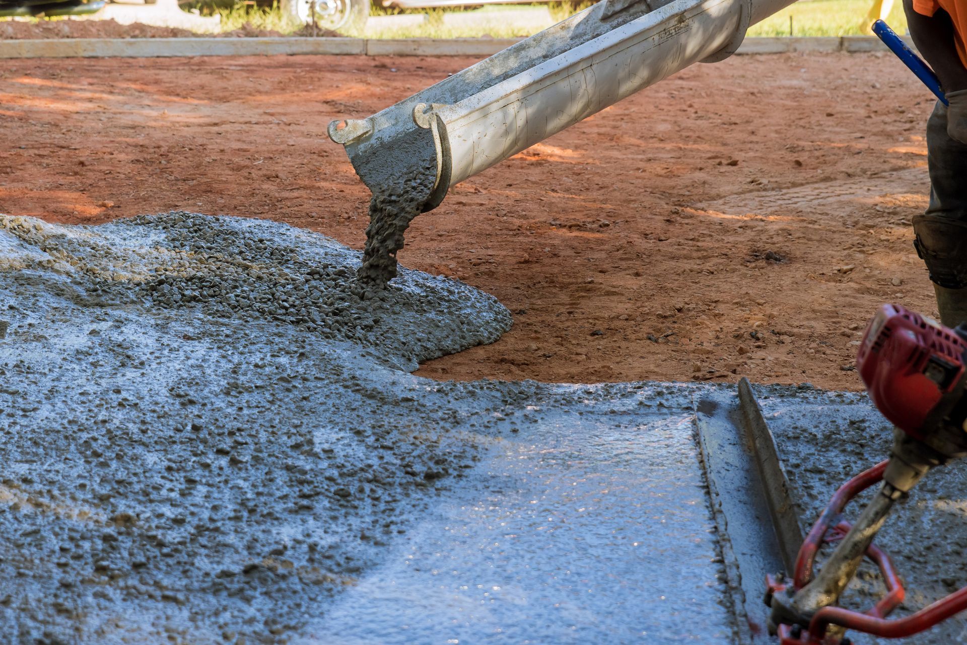 A person is pouring concrete into a concrete slab.