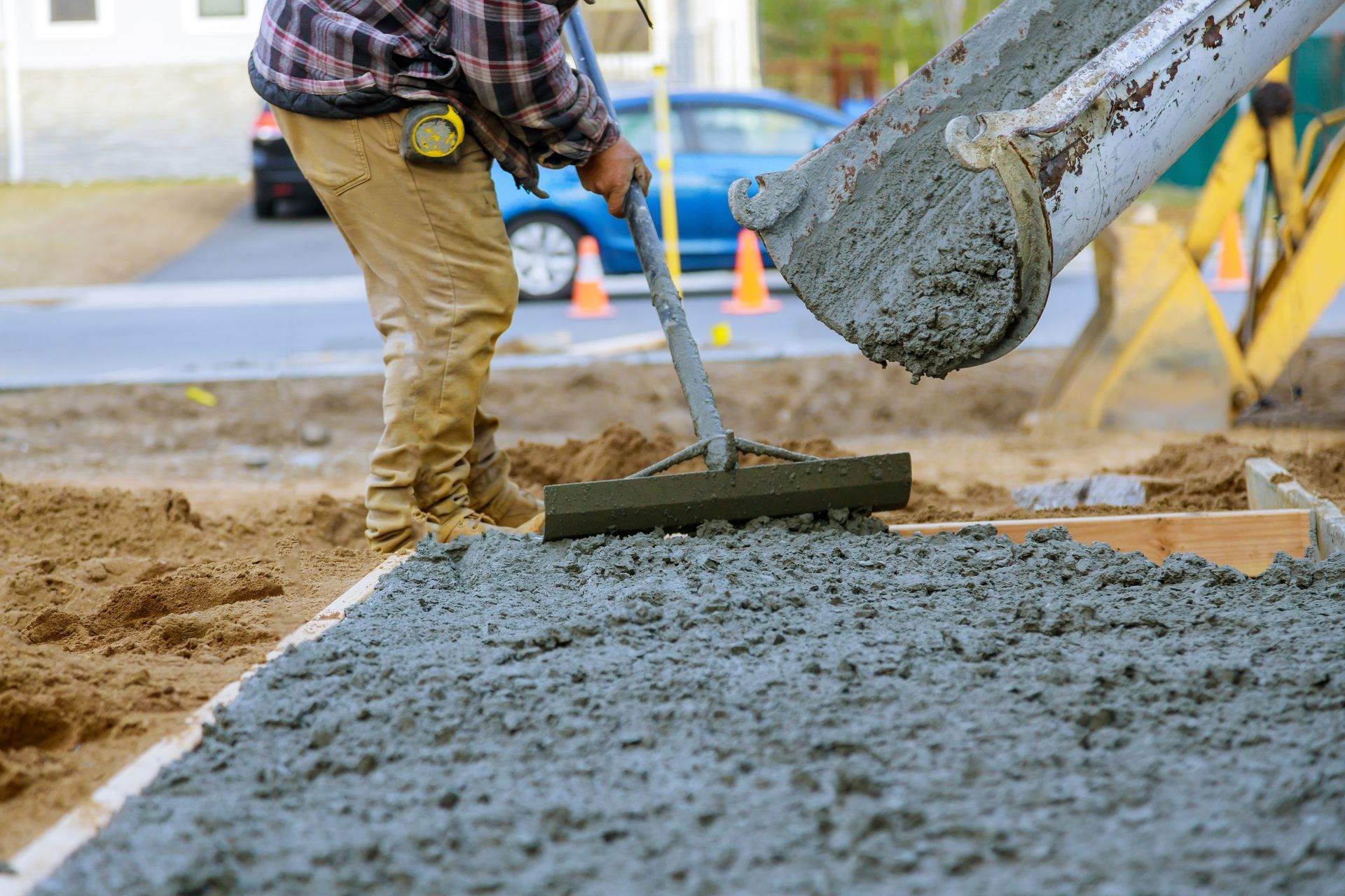 A man is raking concrete on a construction site.