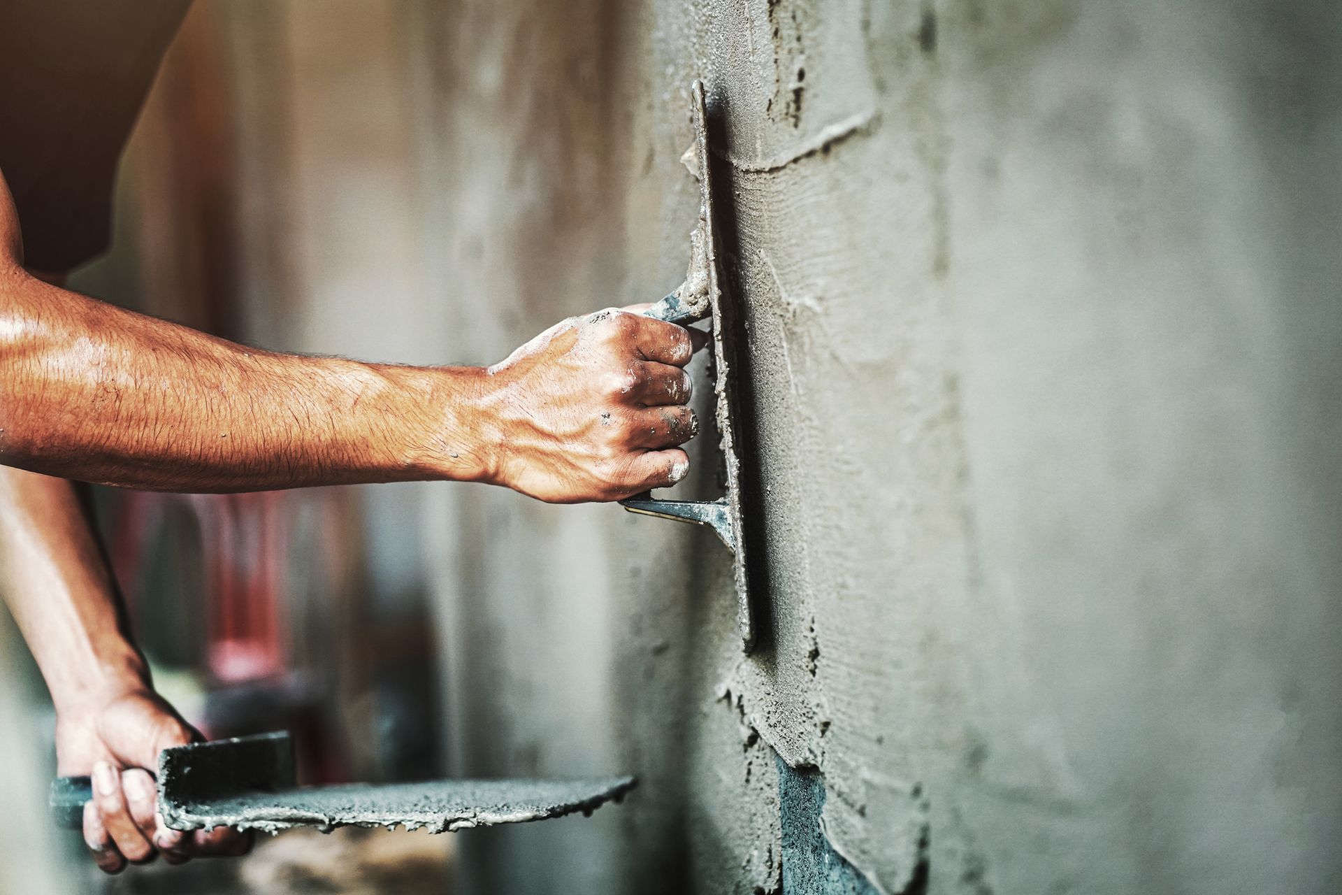 A man is plastering a wall with a trowel.