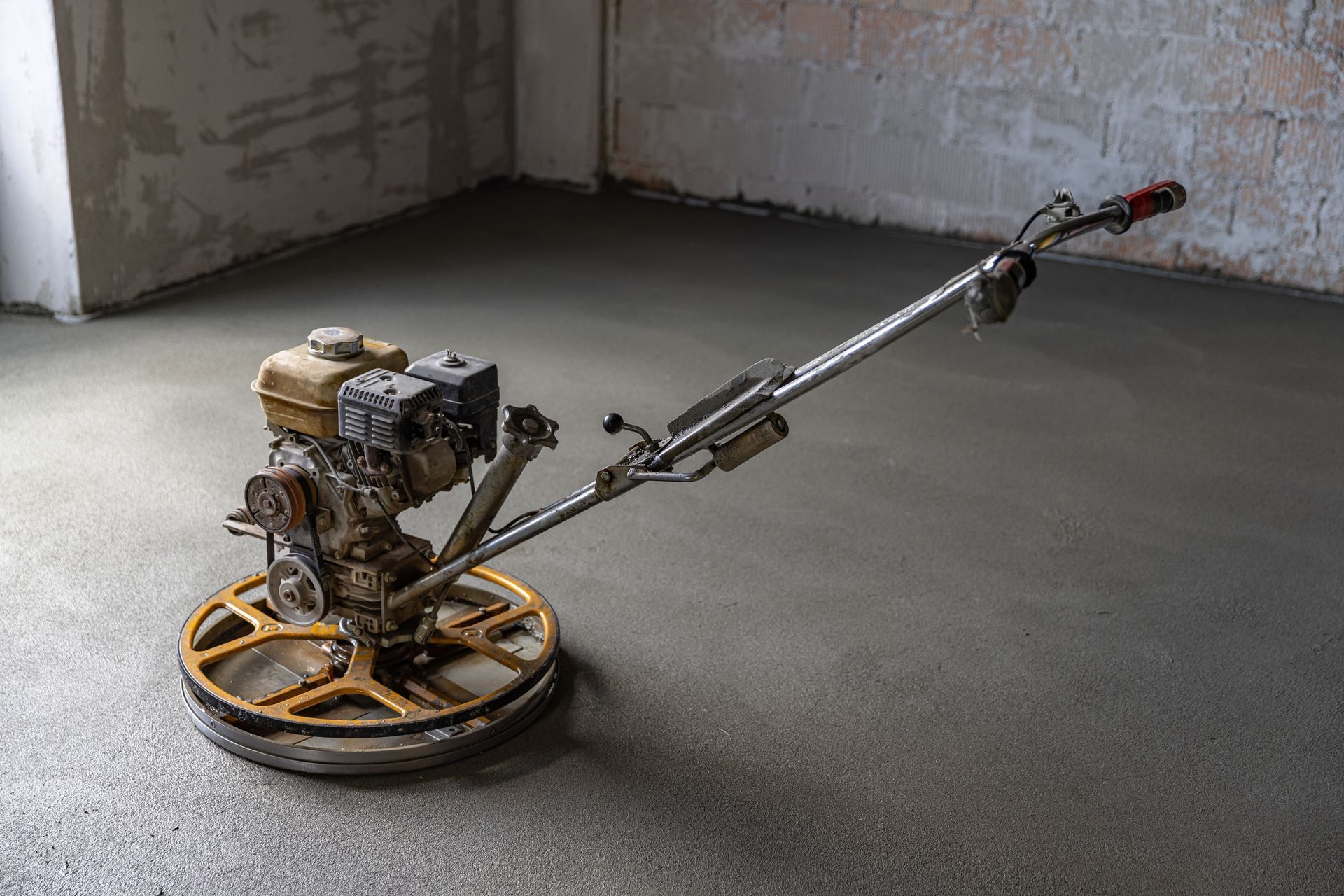 A concrete trowel is sitting on top of a concrete floor in a room.