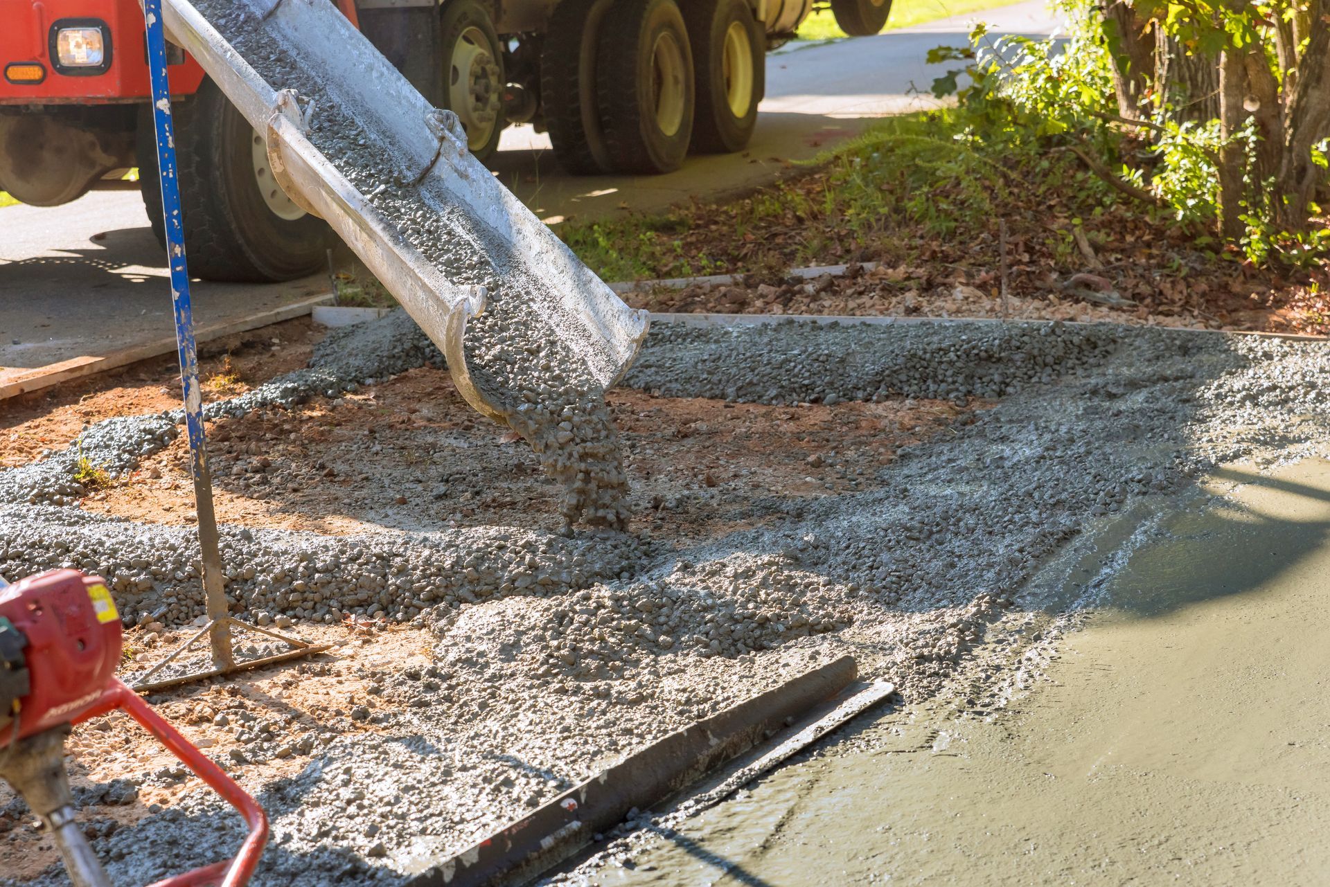 A truck is pouring concrete on a sidewalk.