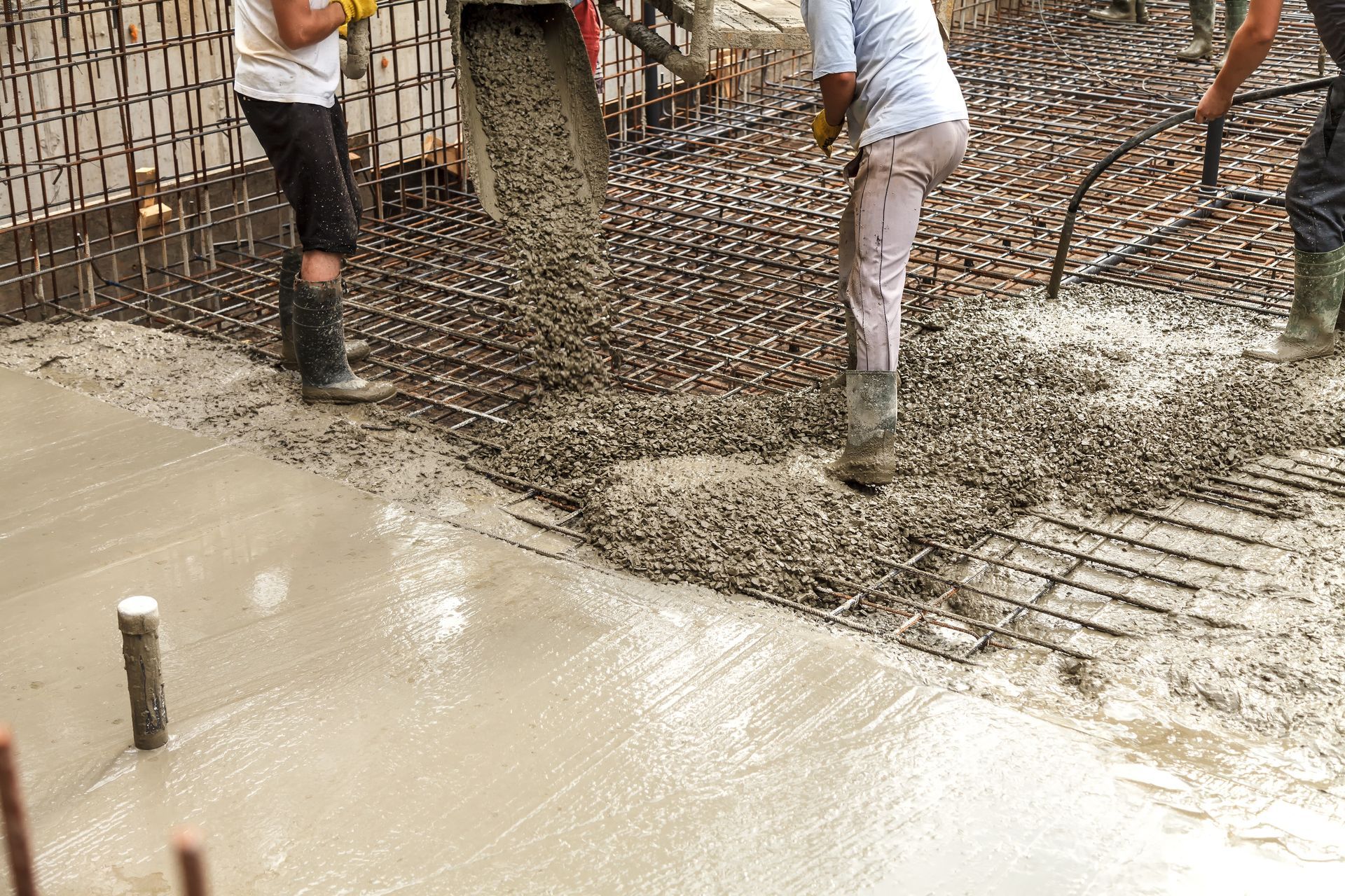 A group of construction workers are pouring concrete on a concrete floor.
