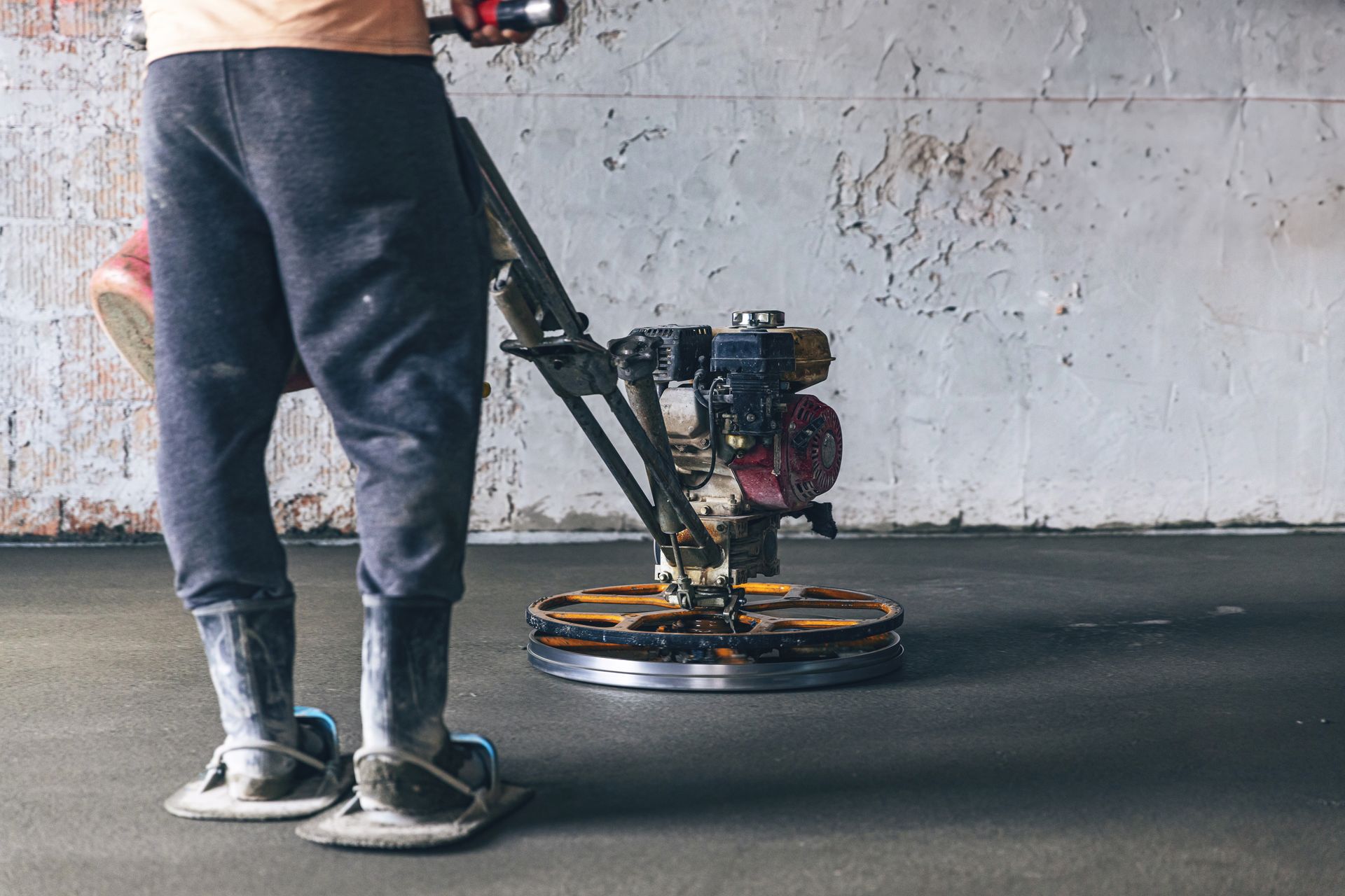 A man is using a machine to finish a concrete floor.
