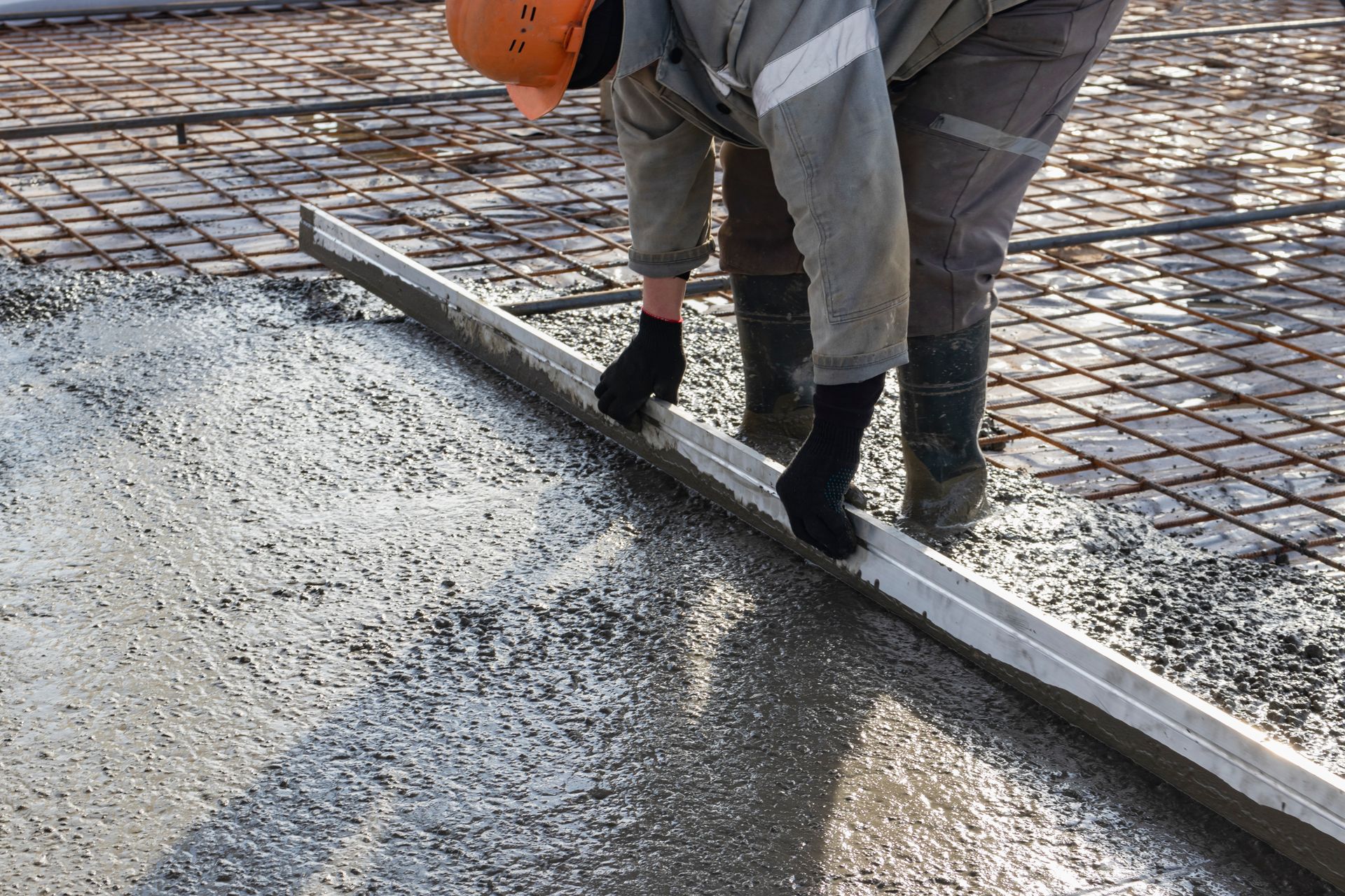 A construction worker is leveling a concrete floor with a level.