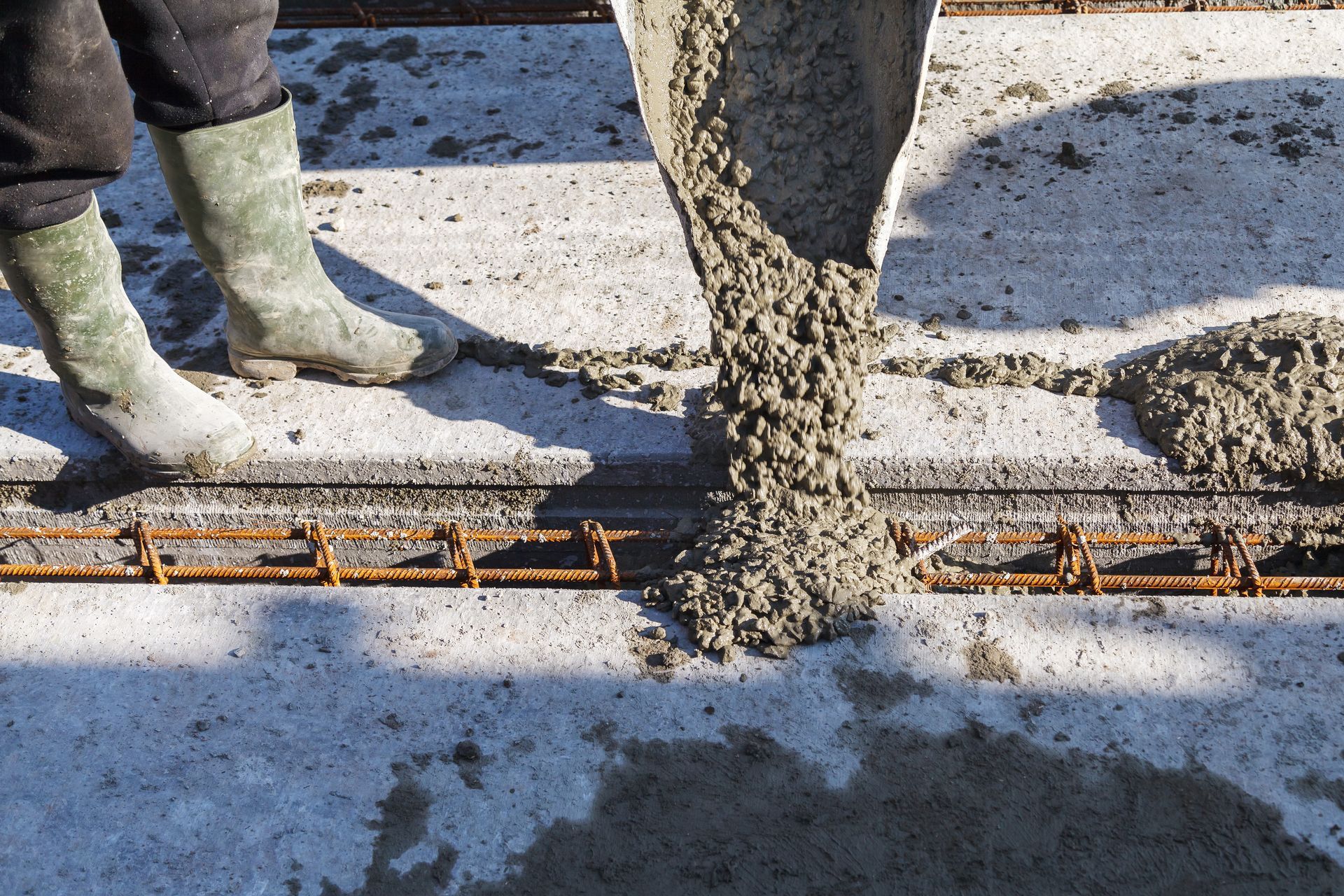 A person is pouring concrete into a concrete slab.