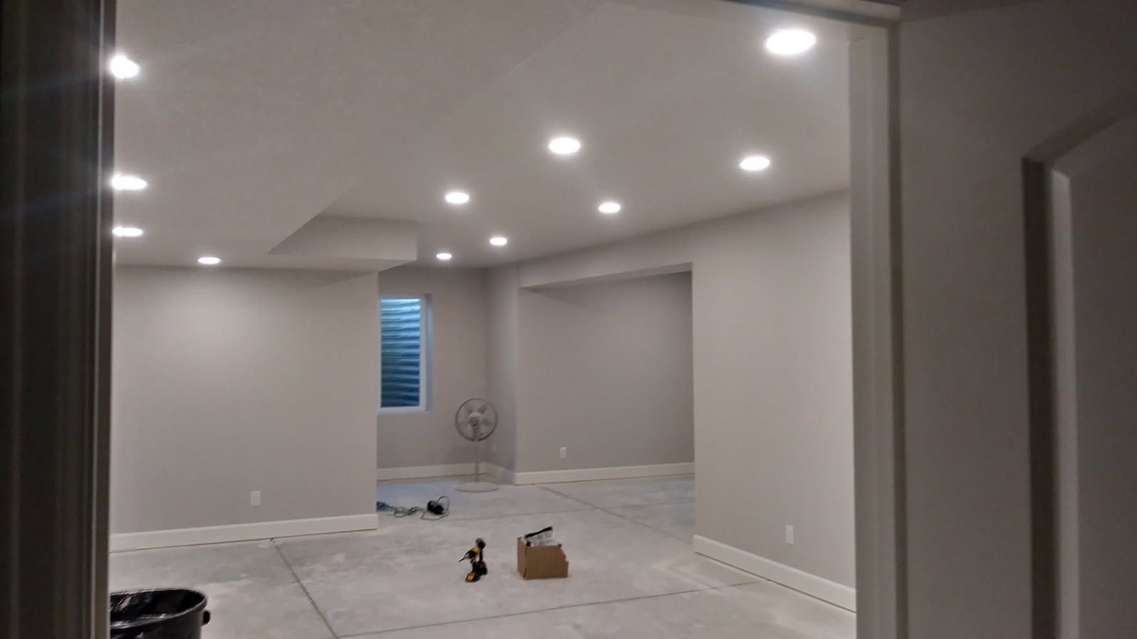 Empty room with recessed lights, gray walls, and unfinished concrete floor.
