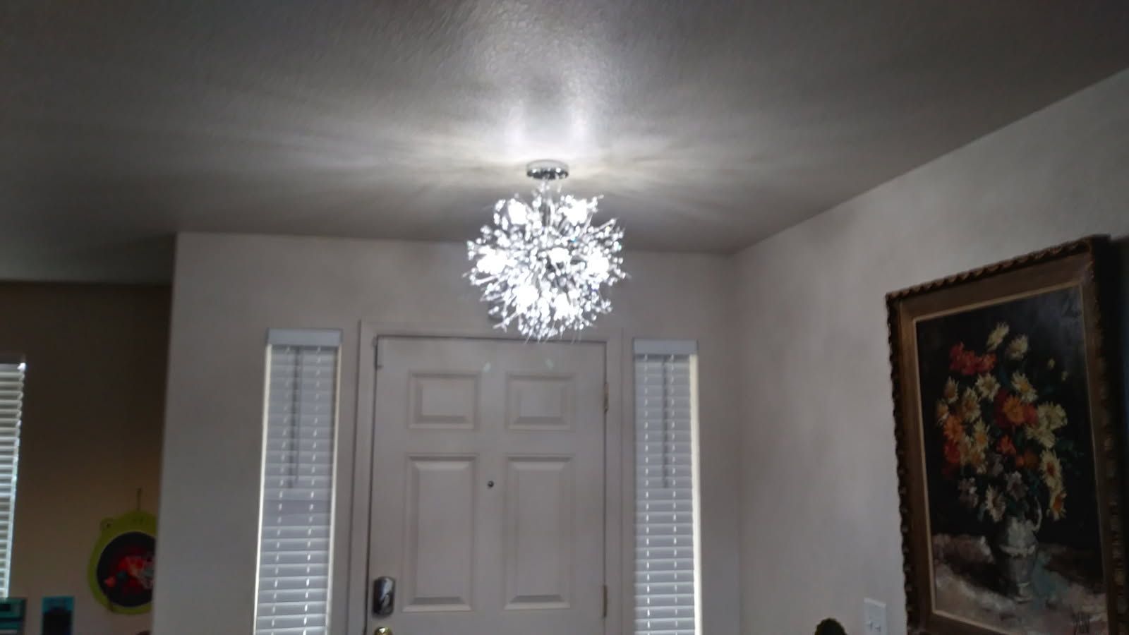 A shiny silver pendant light hanging from the ceiling over a white door.