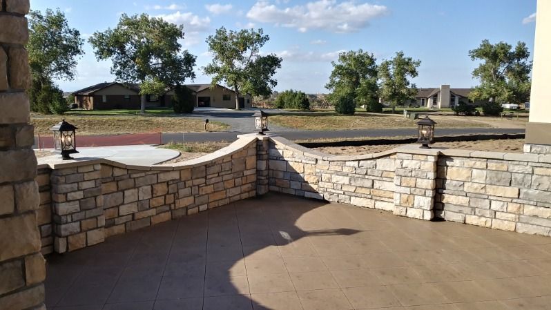 Stone wall with lanterns, overlooking a street and houses on a sunny day.