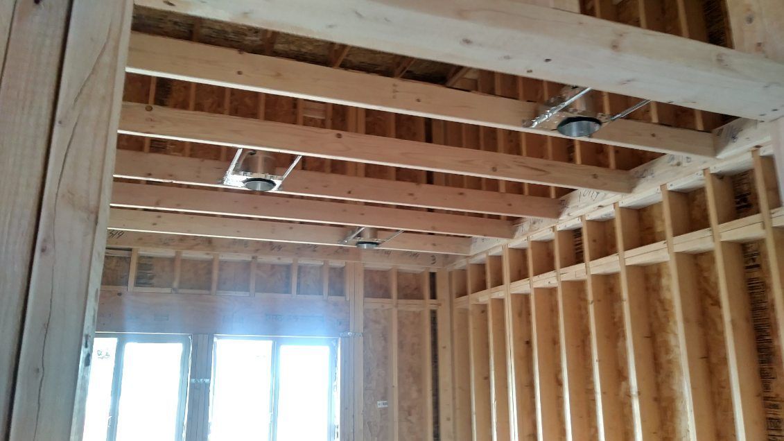 Interior framing of a building under construction with exposed wooden beams and studs.