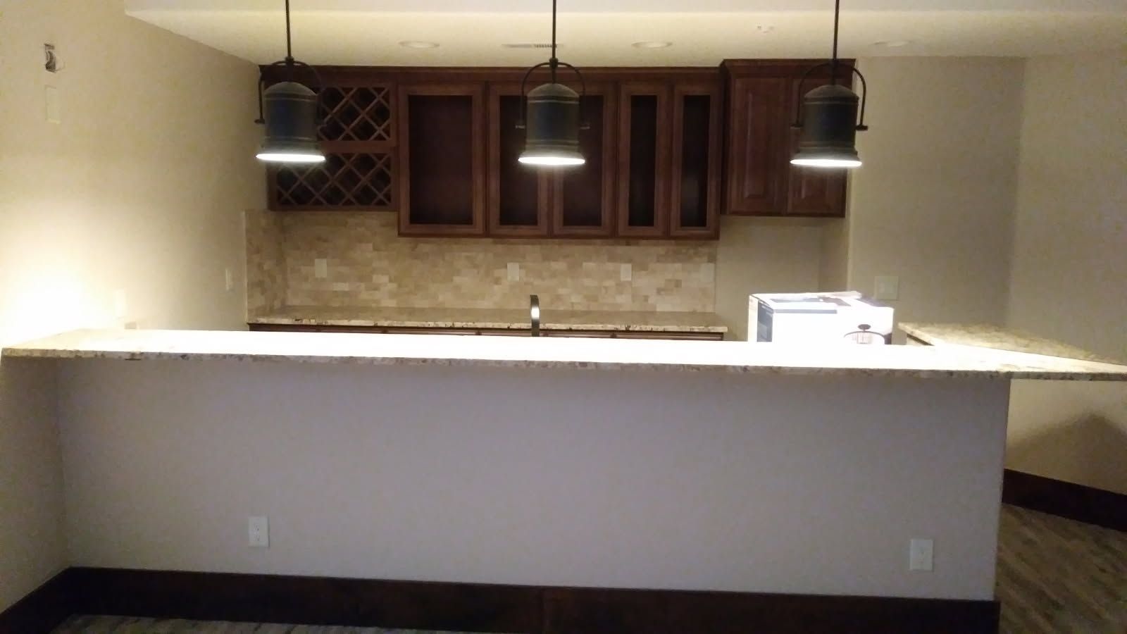 Bar area with granite countertop, cabinets, and pendant lights.