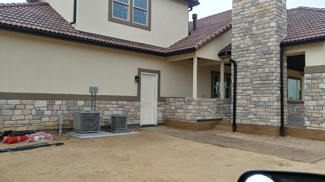 House exterior with stone accents, red tile roof, and a small porch under construction.