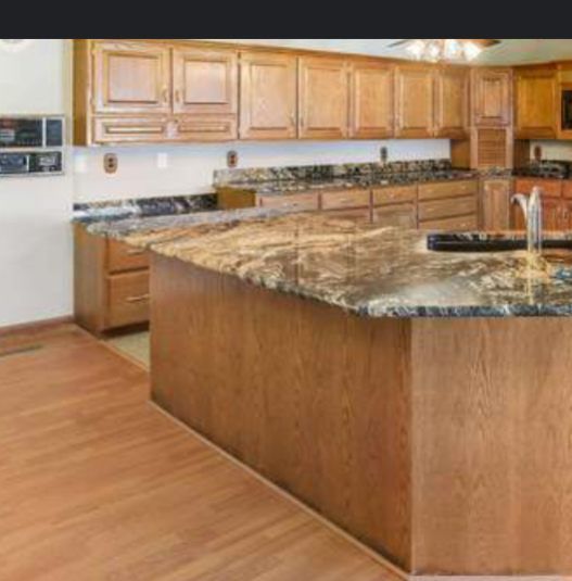 Kitchen with wooden cabinets, granite countertops, and an island with a sink.