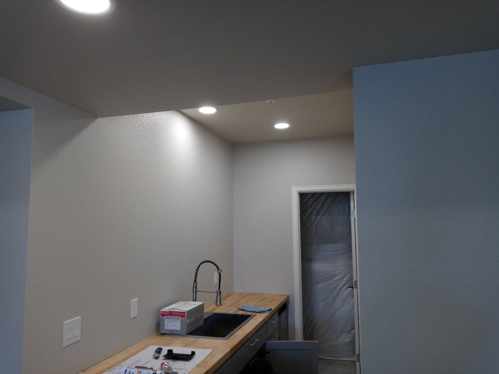 Kitchen with sink, counter, and recessed lighting. An open doorway is visible.