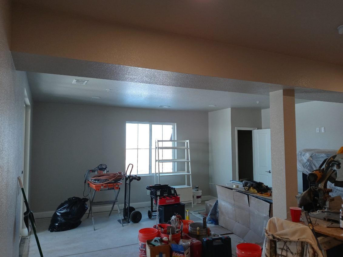 Interior renovation with tools and supplies; grey walls, open doorway, window, beige ceiling.