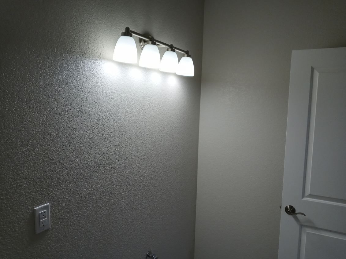 Bathroom with textured wall, light fixture above the sink, and white door.