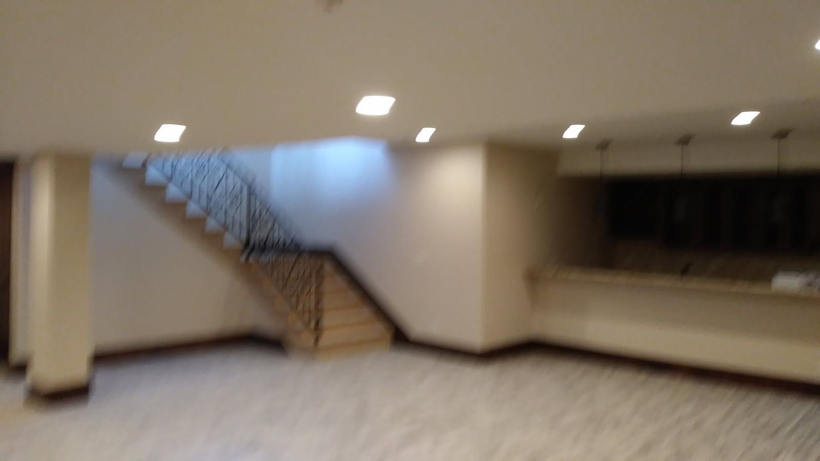 Staircase and countertop in a well-lit beige and white room with a marble floor.