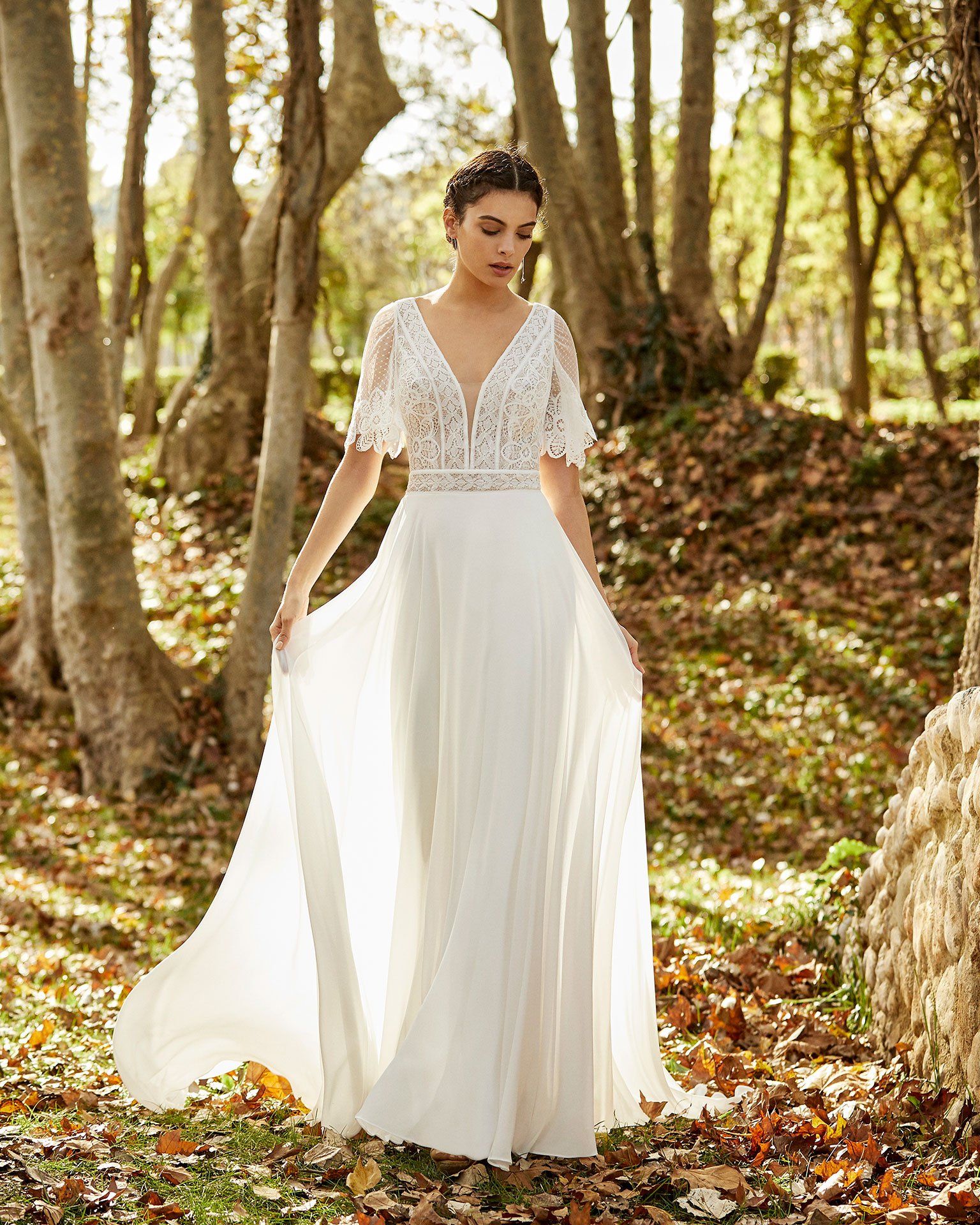 Eine Frau in einem weißen Brautkleid steht im Wald.