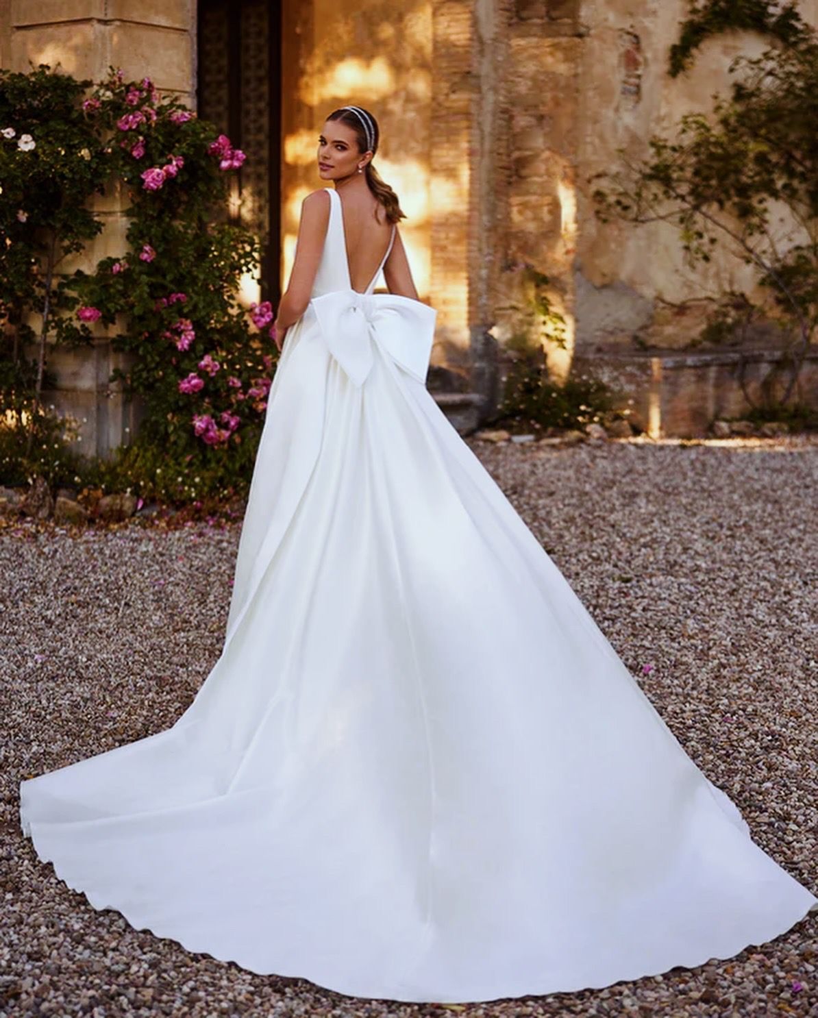 Eine Frau trägt ein weißes Brautkleid mit einer Schleife auf dem Rücken.