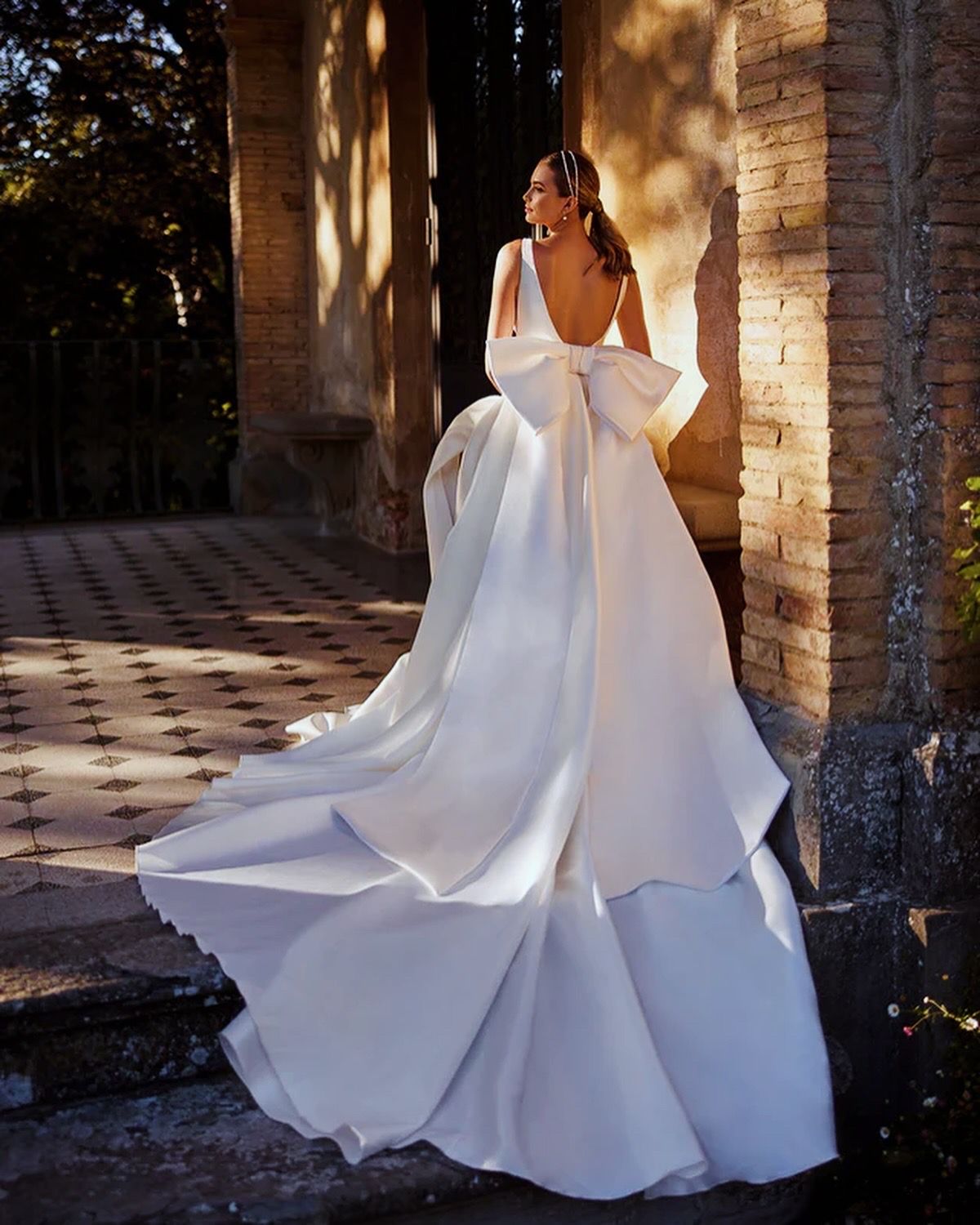 Eine Frau in einem weißen Brautkleid steht vor einem Backsteingebäude.