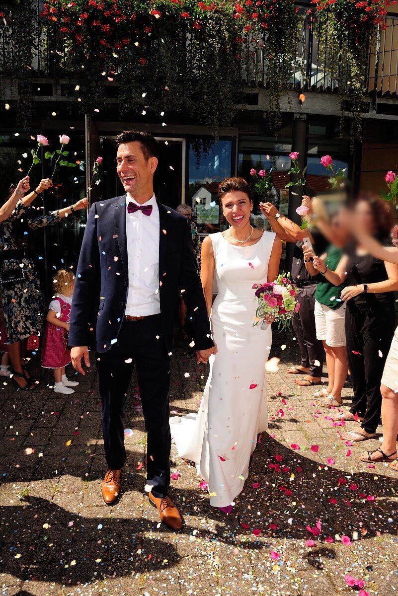 Eine Braut und ein Bräutigam gehen durch eine Menge Konfetti.