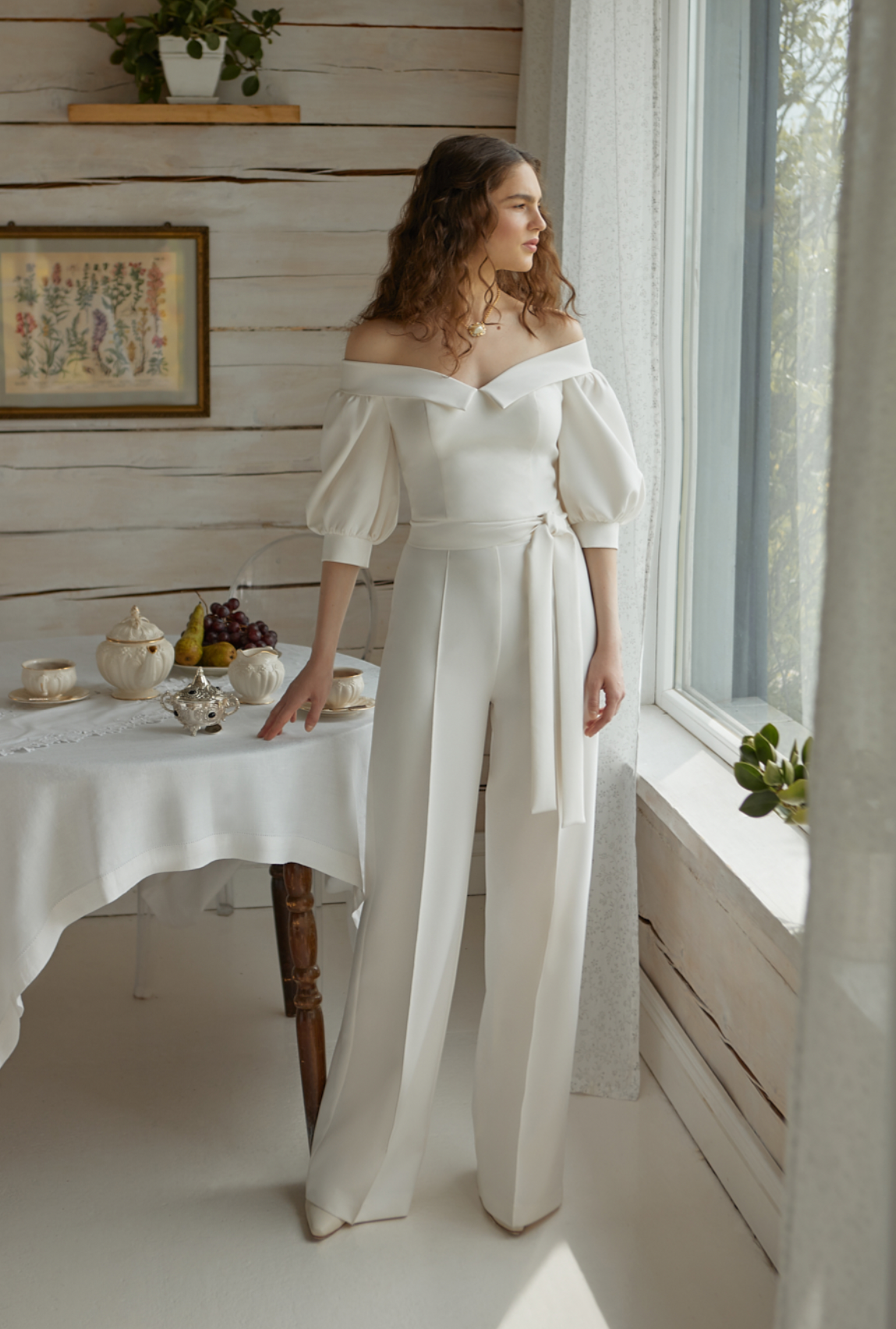 Eine Frau in einem weißen Overall steht vor einem Tisch.