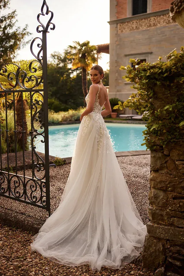 Eine Frau in einem Brautkleid steht vor einem Pool.