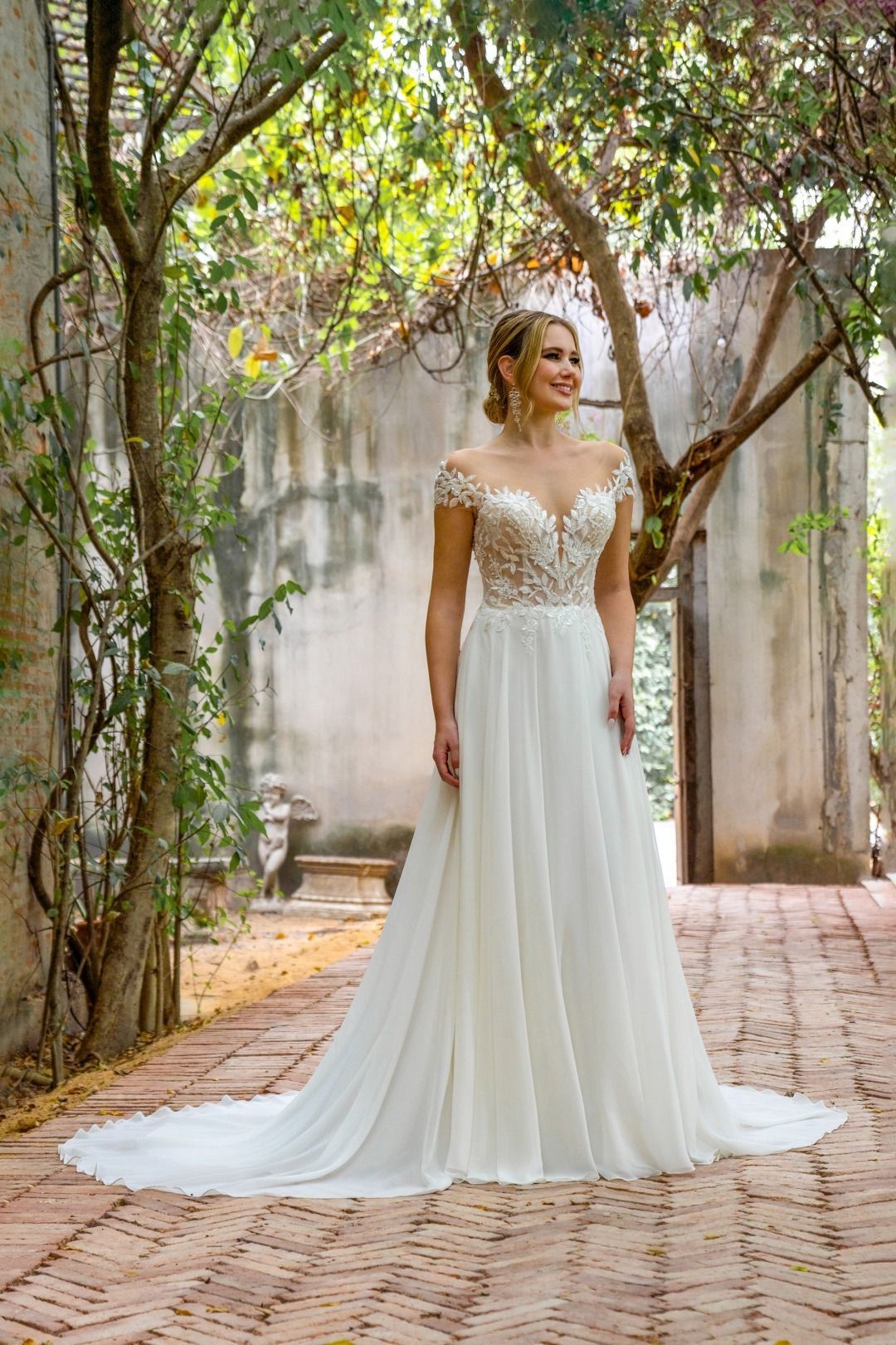 Eine Frau in einem weißen Brautkleid steht vor einem Baum.