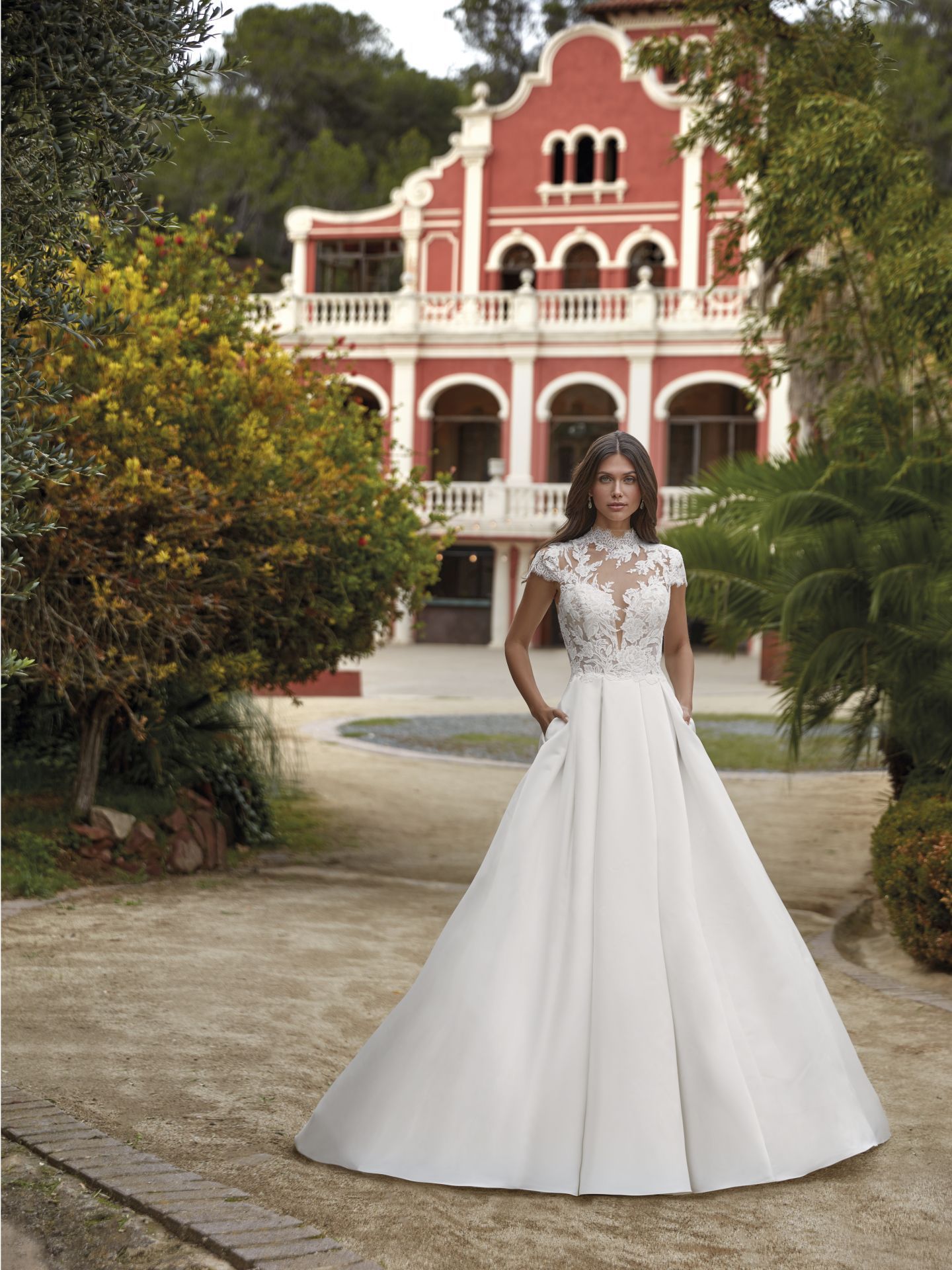 Eine Frau in einem Brautkleid steht vor einem großen roten Gebäude.