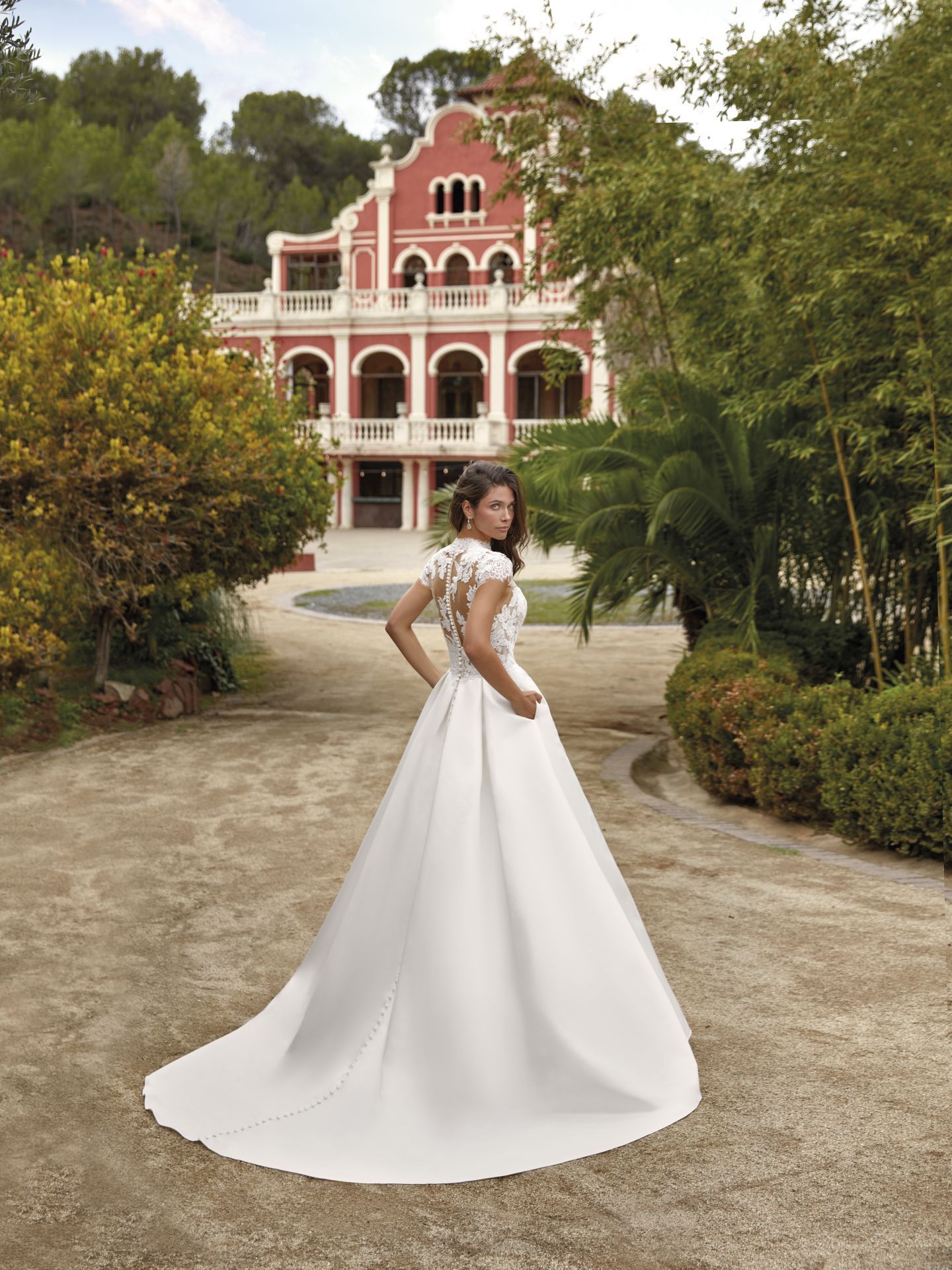 Eine Frau in einem weißen Brautkleid steht vor einem roten Gebäude.