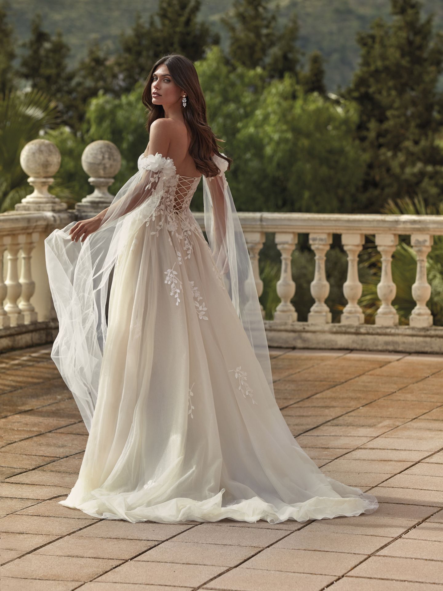 Eine Frau in einem Brautkleid steht auf einem Balkon.