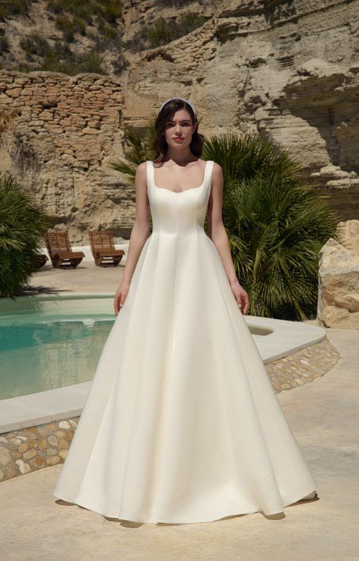 Eine Frau in einem weißen Brautkleid steht neben einem Pool.