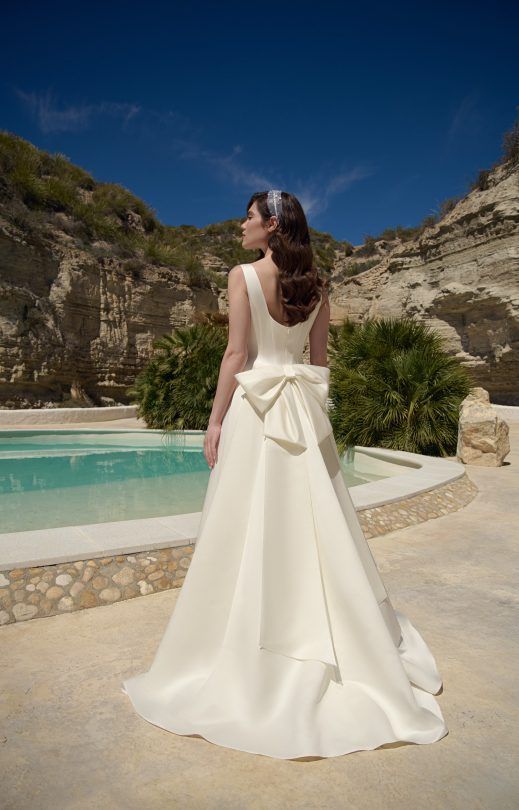 Eine Frau in einem weißen Brautkleid steht vor einem Pool.