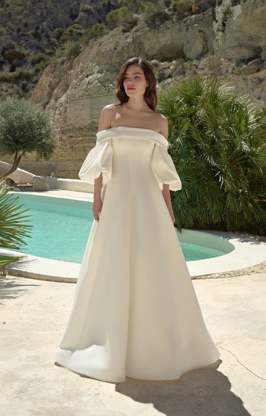 Eine Frau in einem weißen Brautkleid steht neben einem Pool.