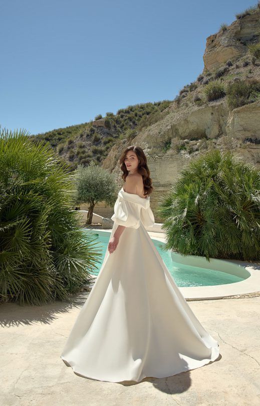 Eine Frau in einem weißen Brautkleid steht neben einem Pool.