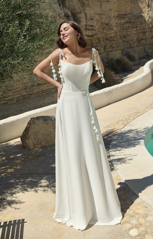 Eine Frau in einem weißen Brautkleid steht neben einem Pool.