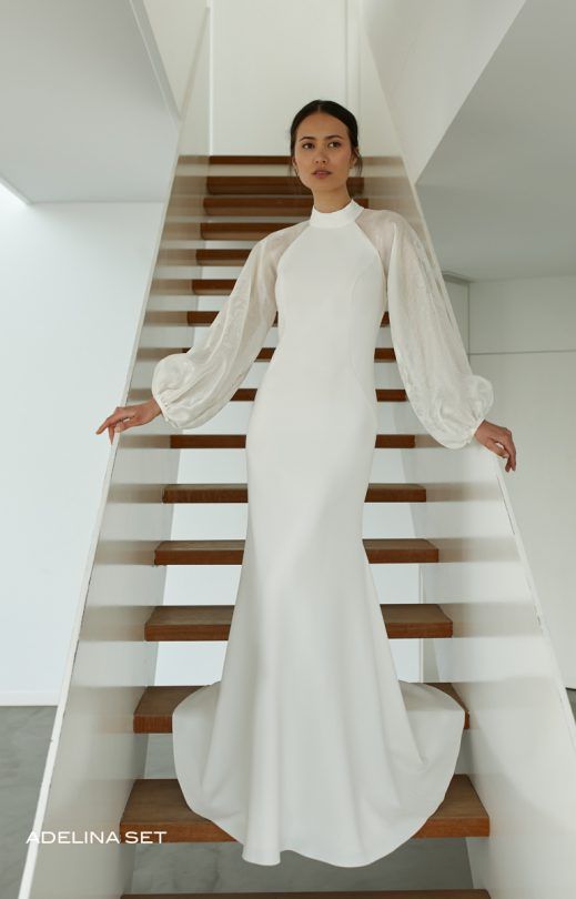 Eine Frau in einem weißen Kleid steht auf einer Treppe.