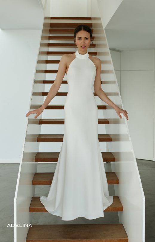 Eine Frau in einem weißen Kleid steht auf einer Treppe.