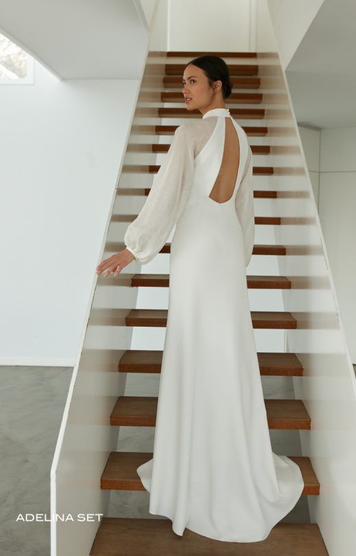 Eine Frau in einem weißen Kleid steht auf einer Treppe.