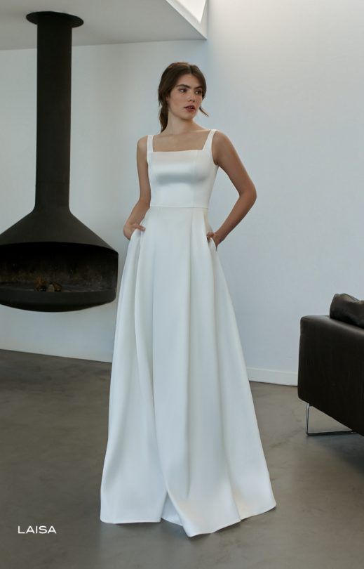 Eine Frau in einem weißen Kleid steht vor einem Kamin.