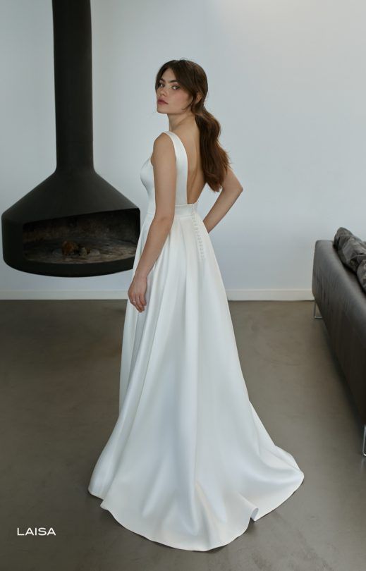 Eine Frau in einem weißen Brautkleid steht vor einem Kamin.