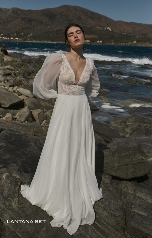 Eine Frau in einem weißen Kleid steht auf einem Felsen in der Nähe des Ozeans.