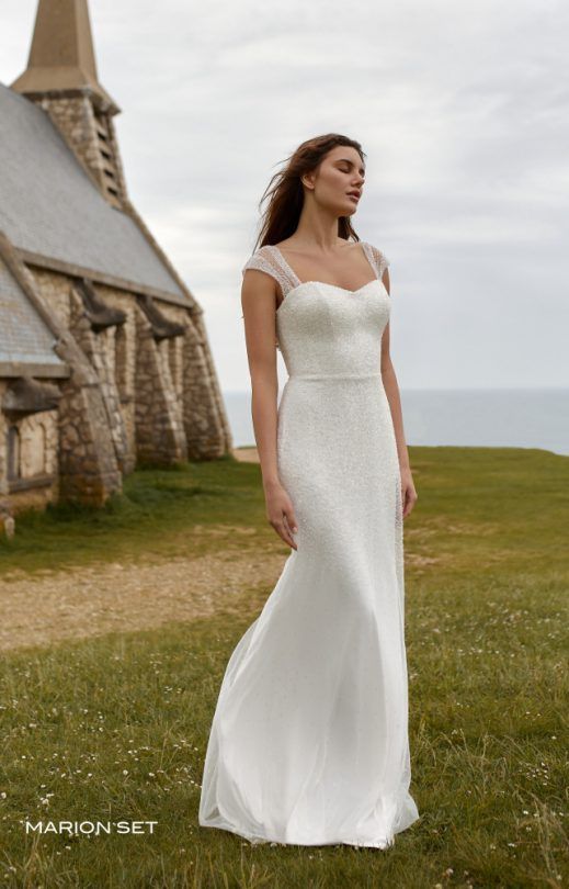 Eine Frau in einem weißen Brautkleid steht vor einer Kirche.