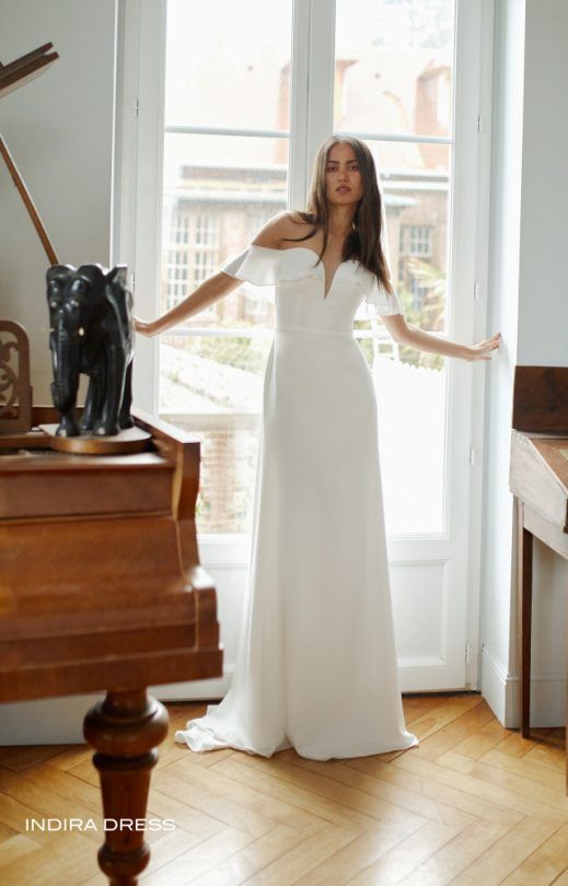 Eine Frau in einem weißen Kleid steht neben einem Klavier.