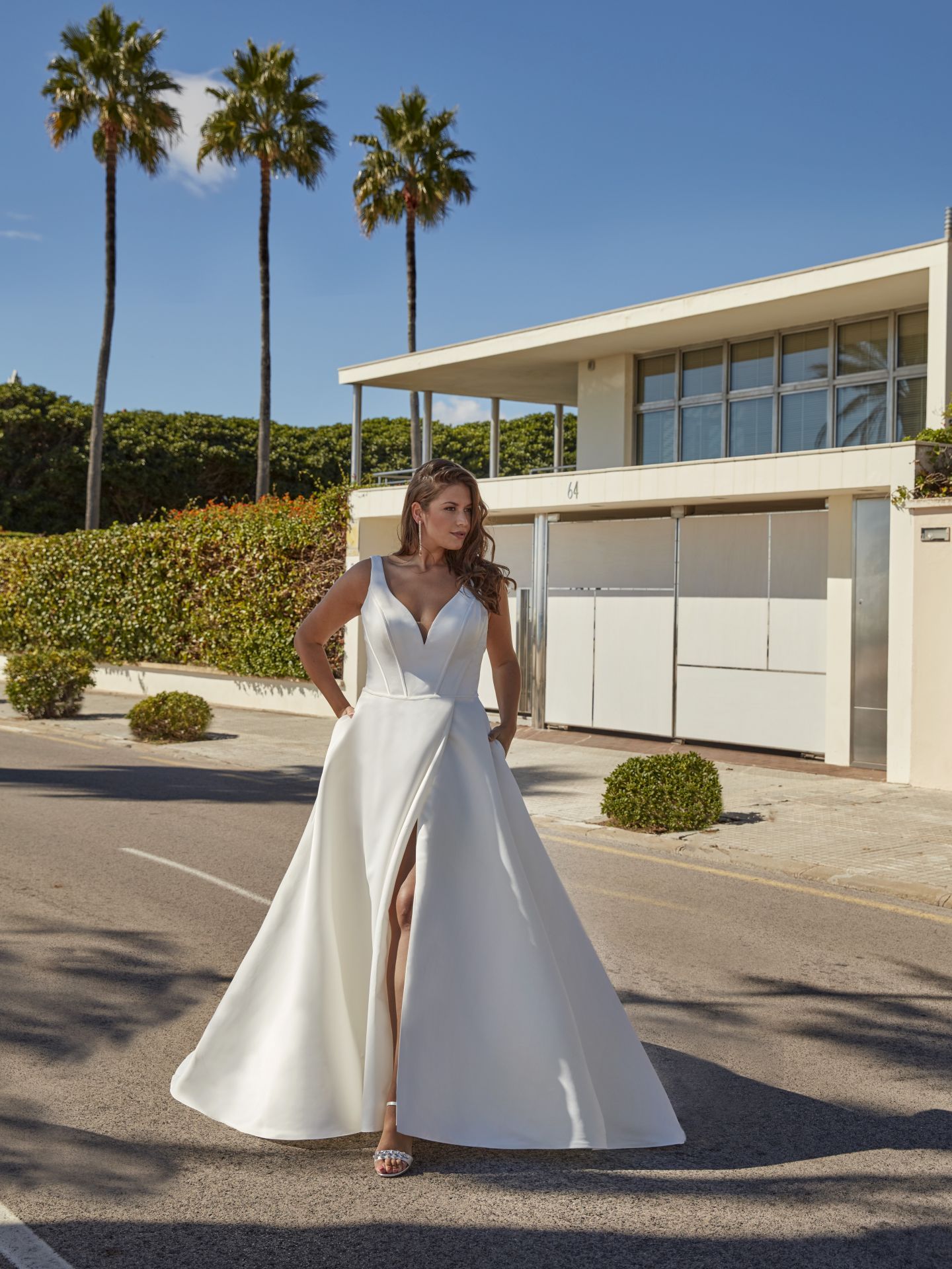 Eine Frau in einem weißen Brautkleid steht vor einem weißen Haus.