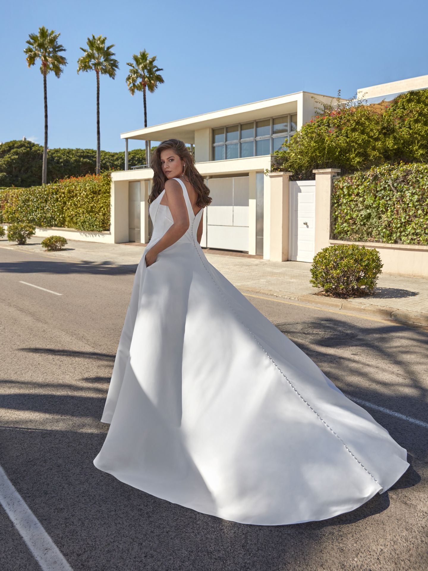 Eine Frau in einem weißen Brautkleid steht vor einem Haus.